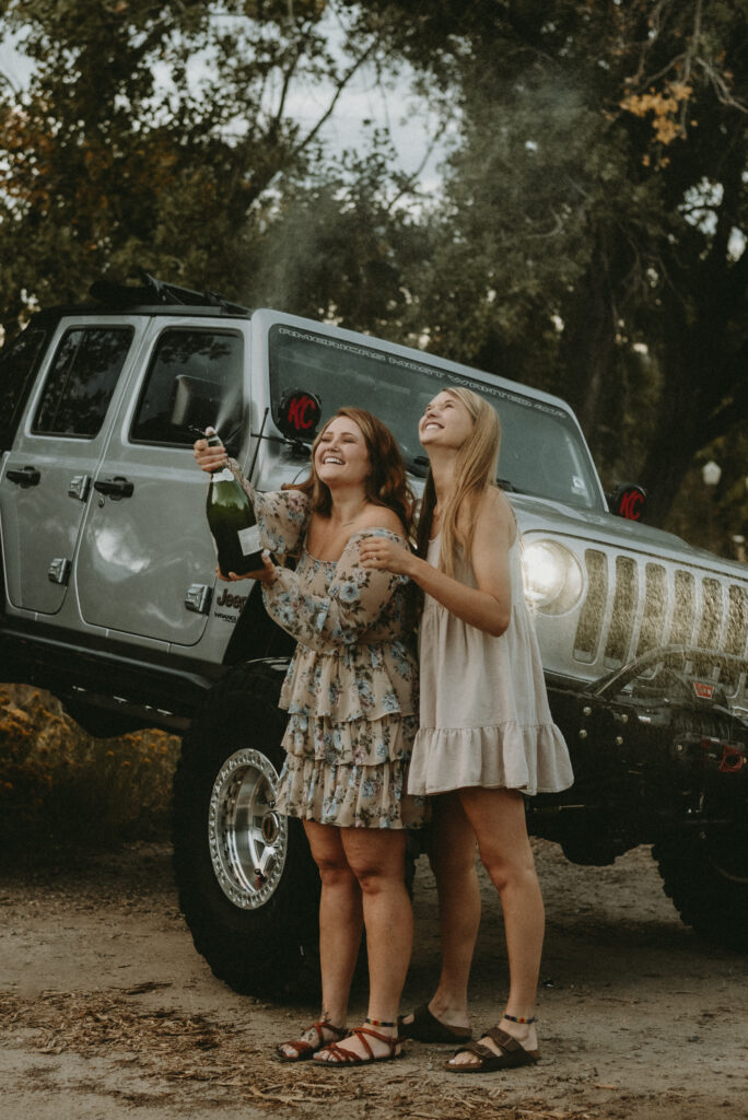 Outdoor Engagement in Colorado Same Sex Couple Popping Champagne with Jeep in Background | Julia Susanne Photography